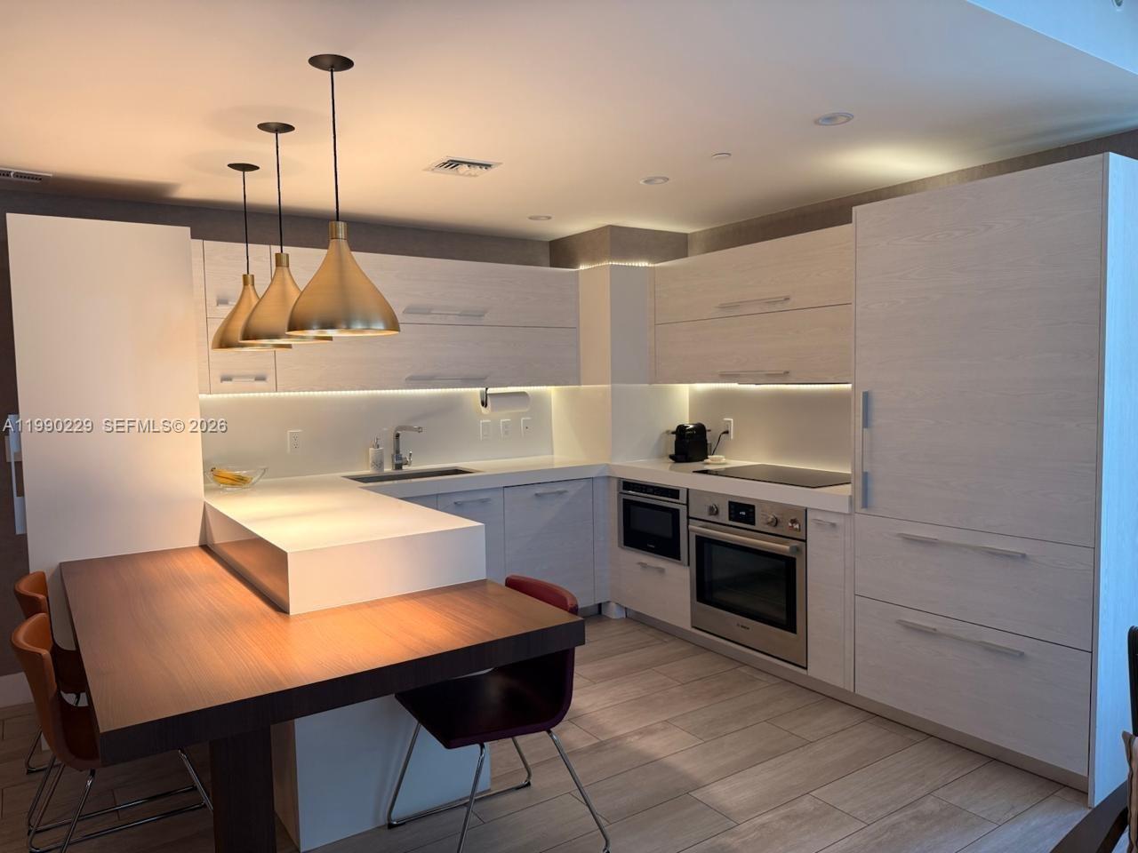 45 Southwest 9th Street, Unit 1401 Miami, FL 33130 - Photo 5 of 17 a kitchen with a stove a sink and a refrigerator