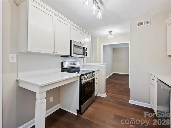 a kitchen with stainless steel appliances granite countertop a stove top oven a sink dishwasher and a refrigerator with wooden floor
