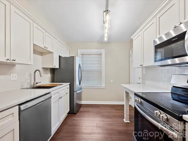 a kitchen with stainless steel appliances a sink dishwasher a stove a microwave oven with cabinets and wooden floor
