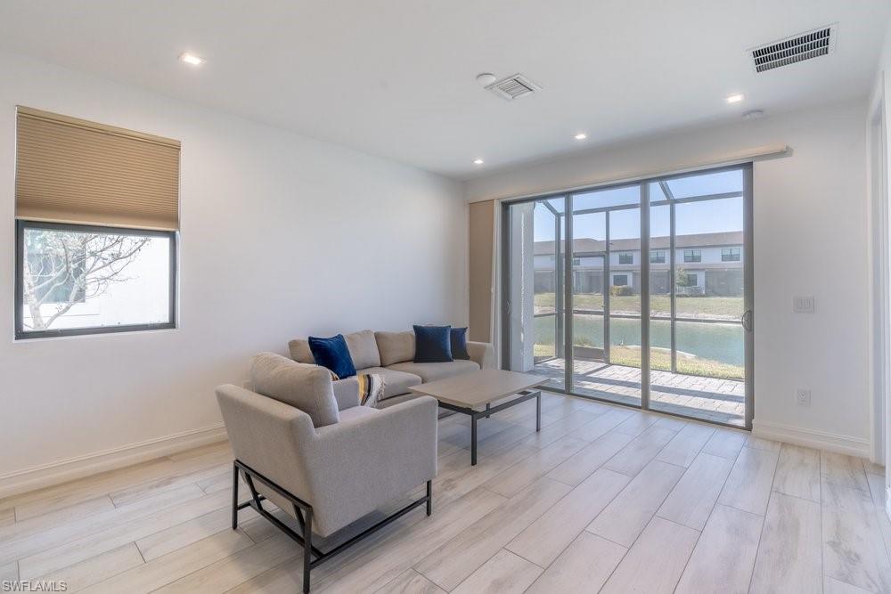 7565 Carnegie Way Naples, FL 34119 - Photo 17 of 50 Living room with wood finish floors, a water view, plenty of natural light, and recessed lighting