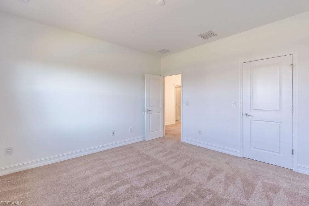7565 Carnegie Way Naples, FL 34119 - Photo 33 of 50 Unfurnished bedroom featuring light carpet and baseboards