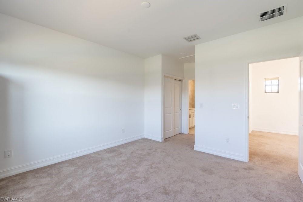 7565 Carnegie Way Naples, FL 34119 - Photo 34 of 50 Unfurnished bedroom with light carpet and a closet