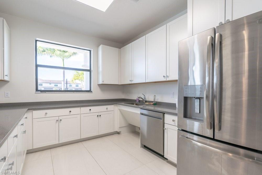7565 Carnegie Way Naples, FL 34119 - Photo 43 of 50 Clubhouse kitchen with stainless steel appliances, white cabinets, dark countertops, and light tile patterned floors