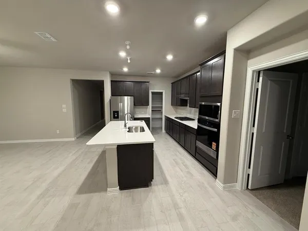 a view of kitchen with stainless steel appliances kitchen island granite countertop a refrigerator and a sink