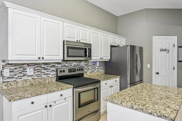 a kitchen with granite countertop a sink stove and refrigerator