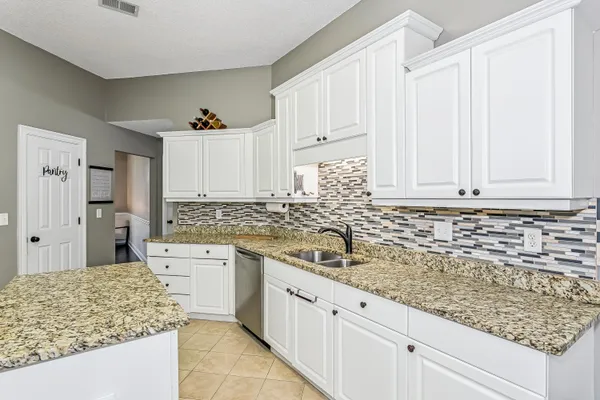 a kitchen with granite countertop white cabinets and white appliances
