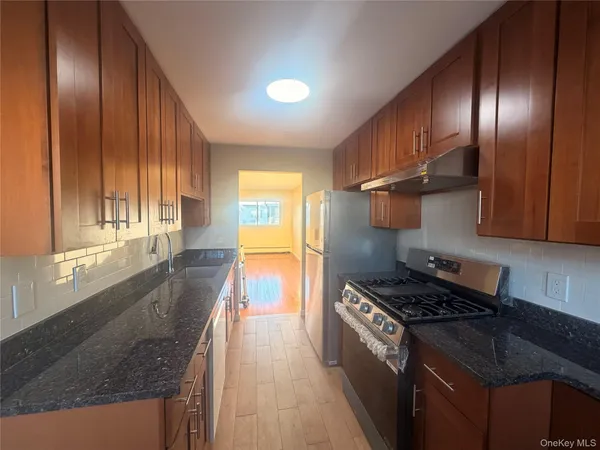 a kitchen with granite countertop stainless steel appliances a sink stove top oven and cabinets