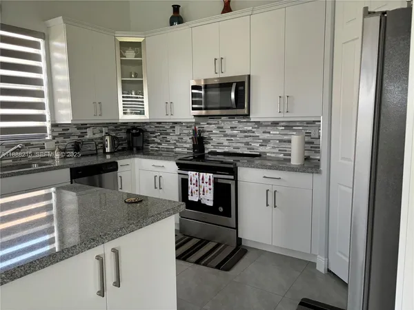 a kitchen with granite countertop a sink stove and microwave