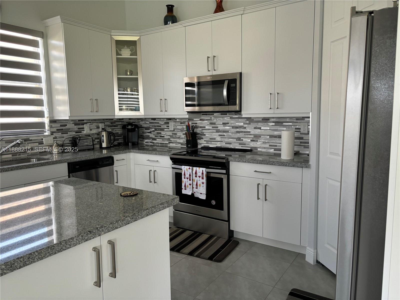5107 Genoa Street, Unit 5107 Ave Maria, FL 34142 - Photo 5 of 16 a kitchen with granite countertop a sink stove and microwave
