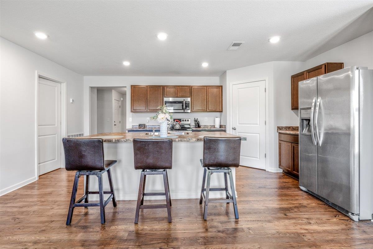 5320 Crossfield Road Memphis, TN 38109 - Photo 17 of 40 a kitchen with stainless steel appliances granite countertop a refrigerator a stove a sink dishwasher and a dining table with wooden floor