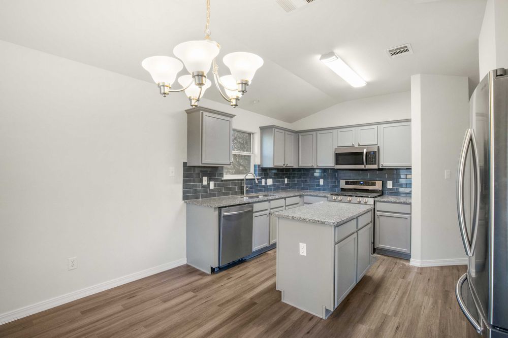 3310 Blue Ridge Drive Round Rock, TX 78681 - Photo 3 of 13 A well-equipped kitchen features a central island, modern stainless steel appliances, and ample grey cabinetry.