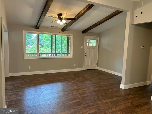 a view of empty room with window and wooden floor