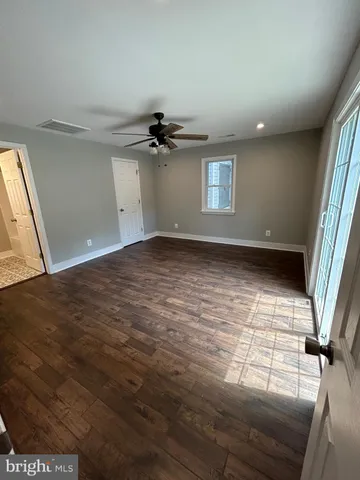 an empty room with wooden floor chandelier fan and windows