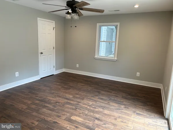 a view of a room with wooden floor and a ceiling fan