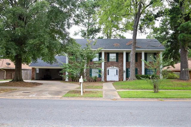 a front view of a house with a garden and trees