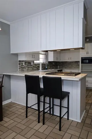 a kitchen with stainless steel appliances granite countertop a table chairs sink and cabinets