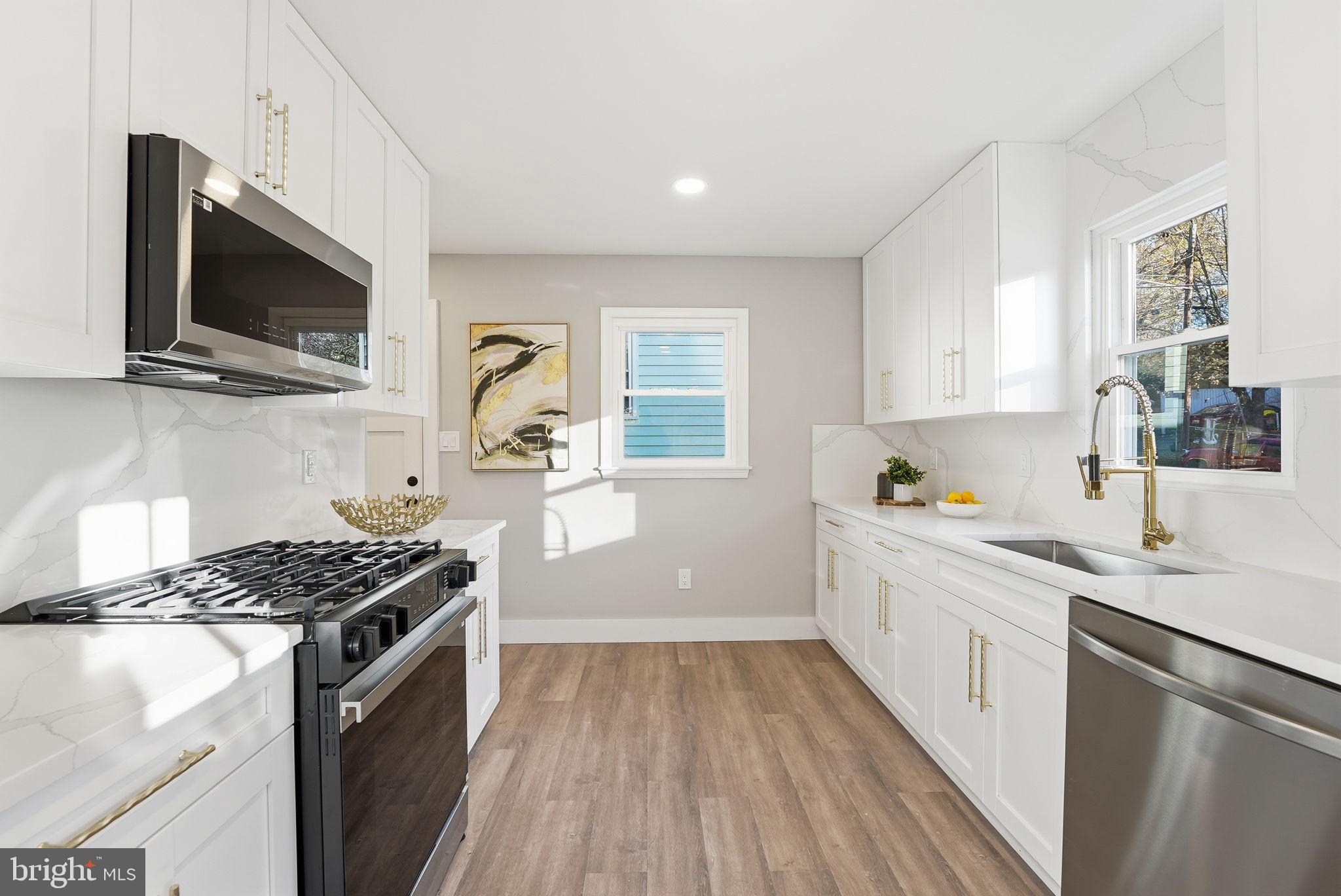 5716 Somerset Road Riverdale, MD 20737 - Photo 4 of 24 a kitchen with stainless steel appliances a sink dishwasher a microwave oven and a stove with wooden floor