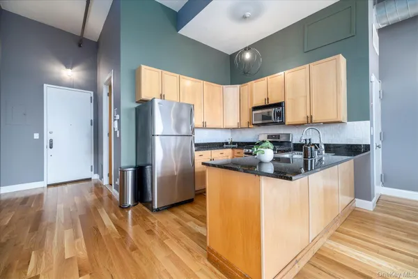 a kitchen with granite countertop a refrigerator a sink a stove a microwave and wooden floor