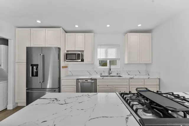 a kitchen with stainless steel appliances a stove a sink a refrigerator and cabinets
