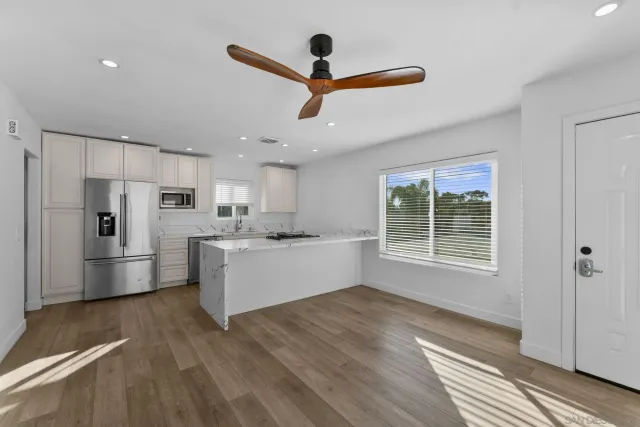 a kitchen with stainless steel appliances kitchen island a refrigerator sink and cabinets