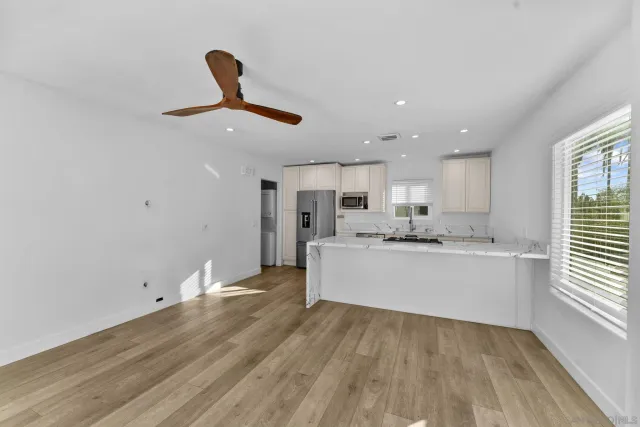 a living room with stainless steel appliances kitchen island hardwood floor sink and window