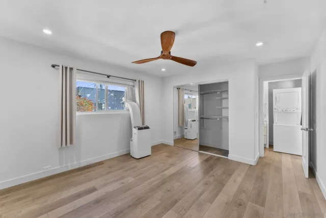 a view of an empty room with window and wooden floor
