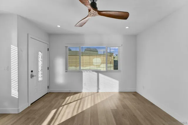 a view of an empty room with wooden floor and a window