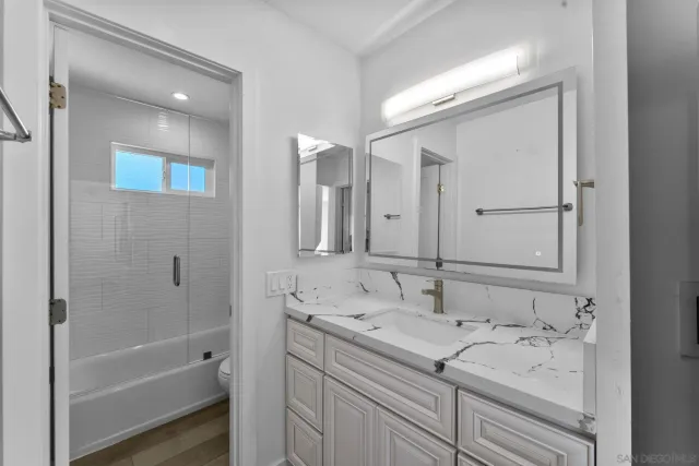 a bathroom with a tub sink double vanity and mirror