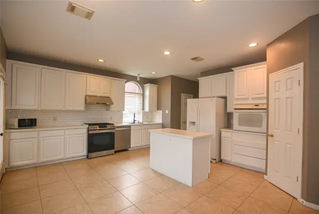 a kitchen with white cabinets and white appliances