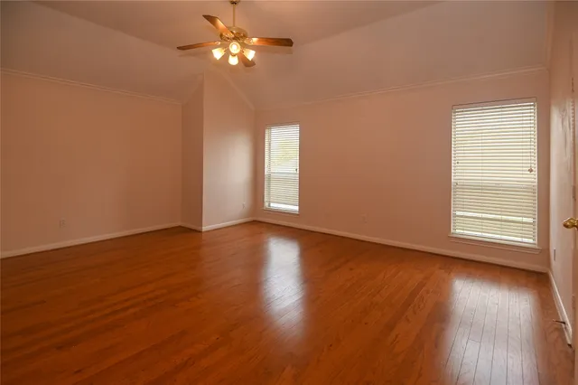 a view of empty room with wooden floor and fan