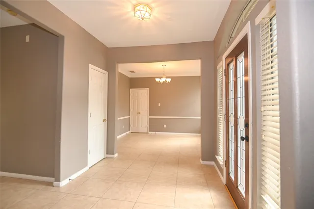 a view of a hallway with a chandelier fan and windows