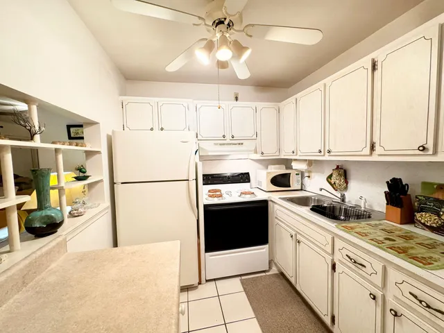 a kitchen with stainless steel appliances granite countertop a refrigerator a sink dishwasher a stove and white cabinets with wooden floor