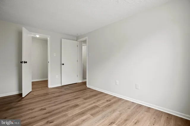 a view of an empty room with wooden floor and closet