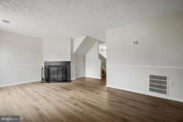 a view of empty room with wooden floor and fireplace
