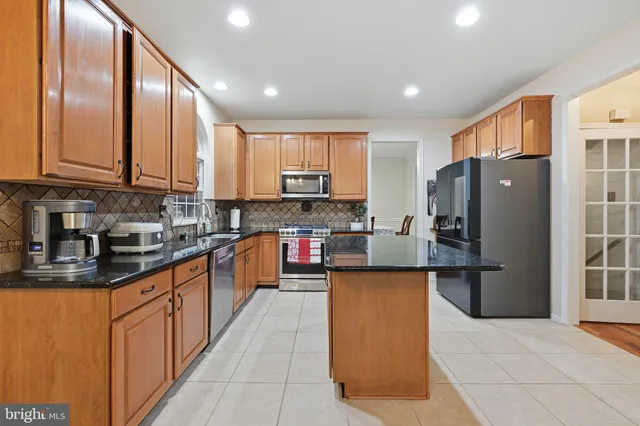 a kitchen with stainless steel appliances granite countertop a refrigerator a stove top oven and a sink