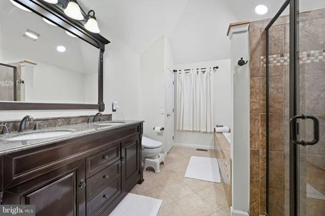 a spacious bathroom with a granite countertop sink a toilet a mirror and shower