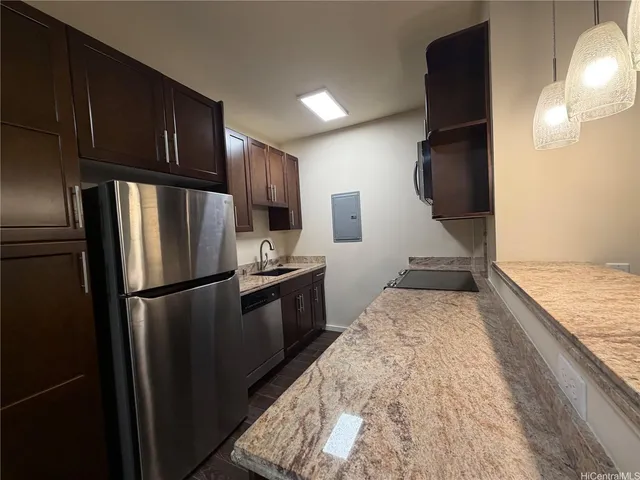 a kitchen with granite countertop a refrigerator a sink and wooden cabinets