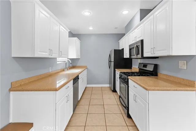 a kitchen with stainless steel appliances granite countertop a stove a refrigerator and a white cabinets