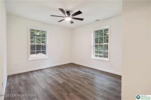 an empty room with windows and fan