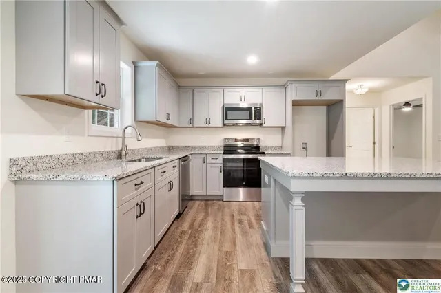 a kitchen with stainless steel appliances granite countertop a stove top oven a sink dishwasher and a refrigerator with wooden floor