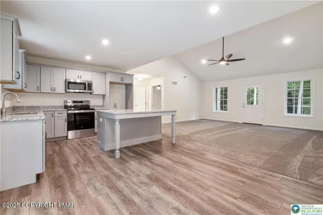 a kitchen with stainless steel appliances granite countertop a stove top oven a sink dishwasher and a refrigerator with wooden floor