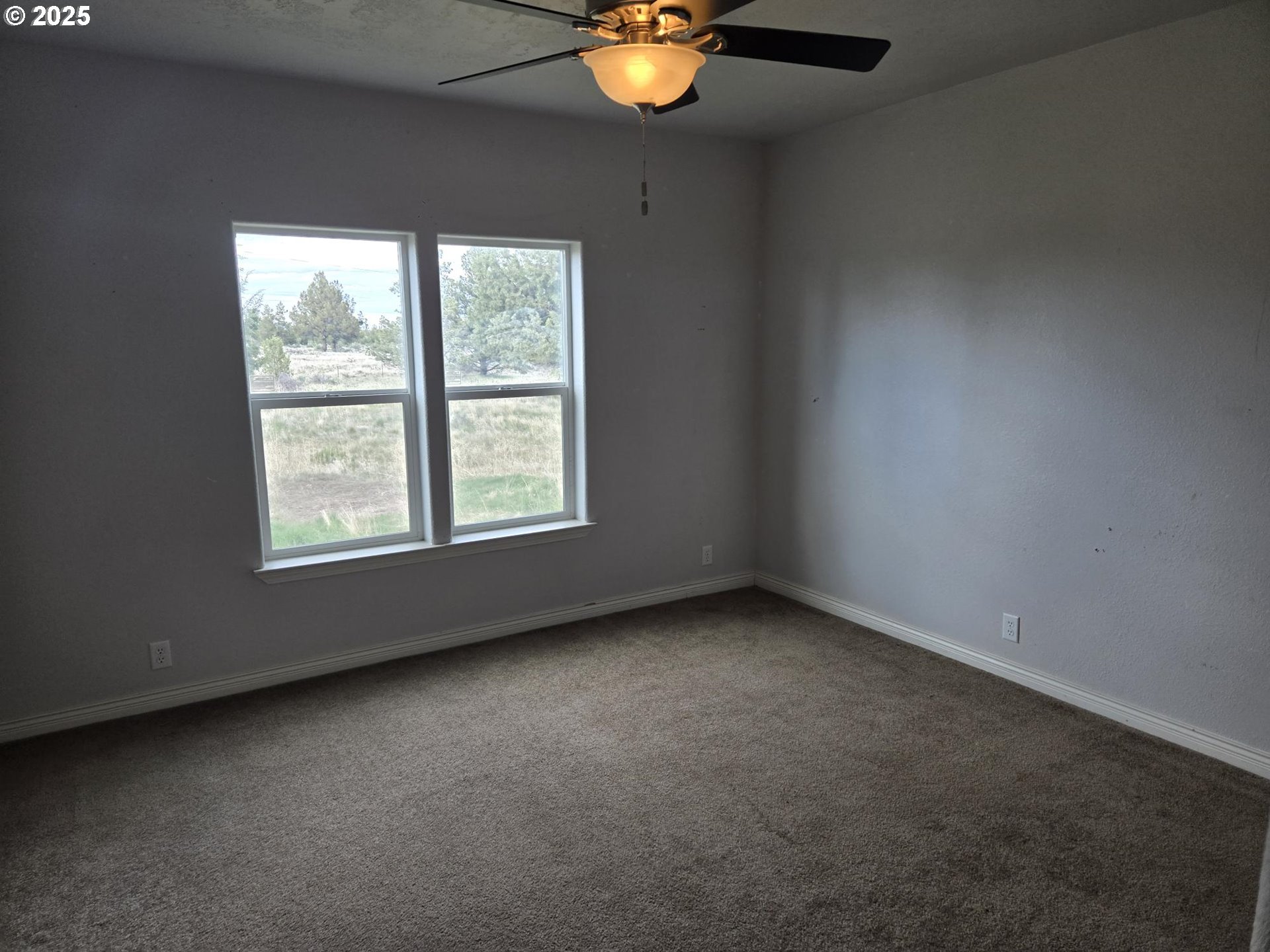 9290 Southwest 3115th Road Culver, OR 97734 - Photo 19 of 21 an empty room with windows and chandelier fan