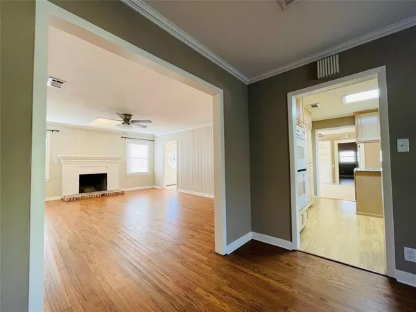 a view of a livingroom with a fireplace a ceiling fan and wooden floor