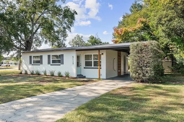 a view of a house with a yard and large tree