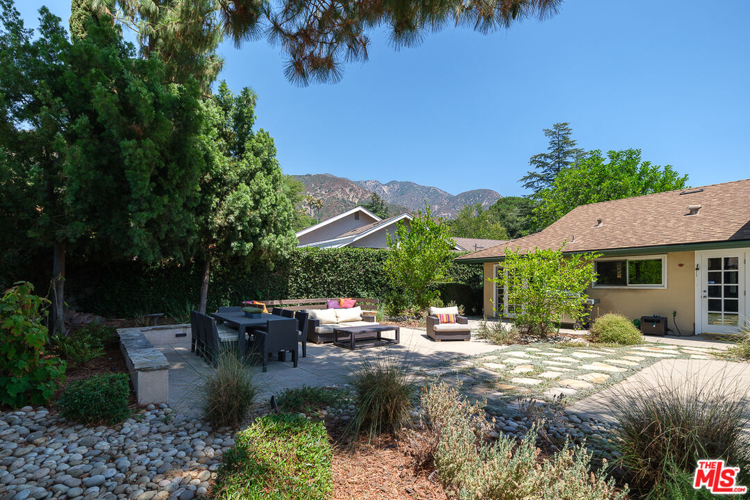 3363 Monterosa Drive Altadena, CA 91001 - Photo 8 of 10 a view of a patio with couches table and chairs under an umbrella with palm trees