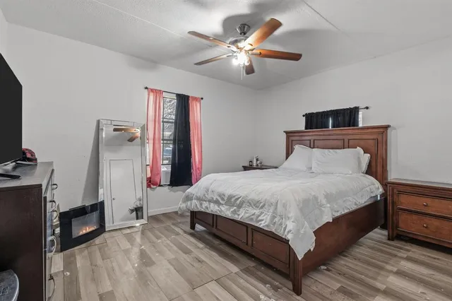 a spacious bedroom with a bed and a flat tv screen on dresser