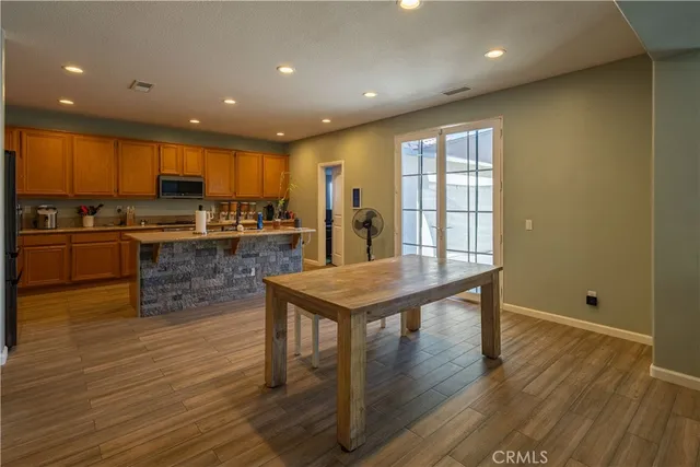 a kitchen with stainless steel appliances granite countertop a stove top oven a sink dishwasher a refrigerator and white cabinets with wooden floor