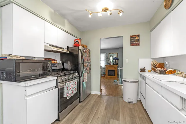 a kitchen that has a lot of cabinets stainless steel appliances and a counter top space