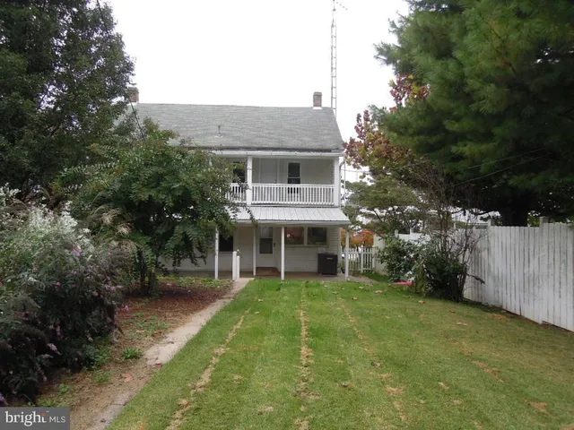 a view of a big house with a yard and large trees