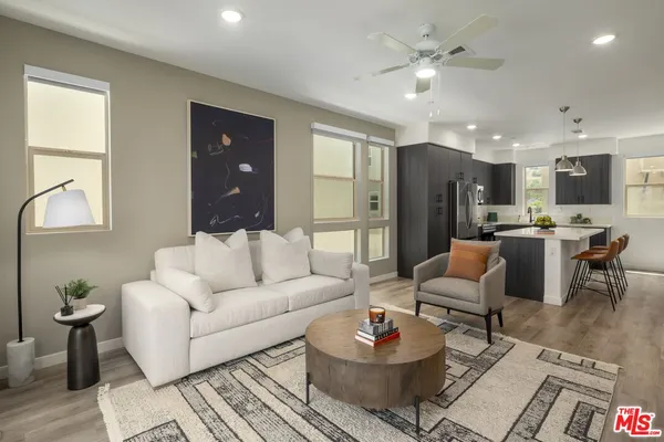 a living room with furniture kitchen view and a chandelier